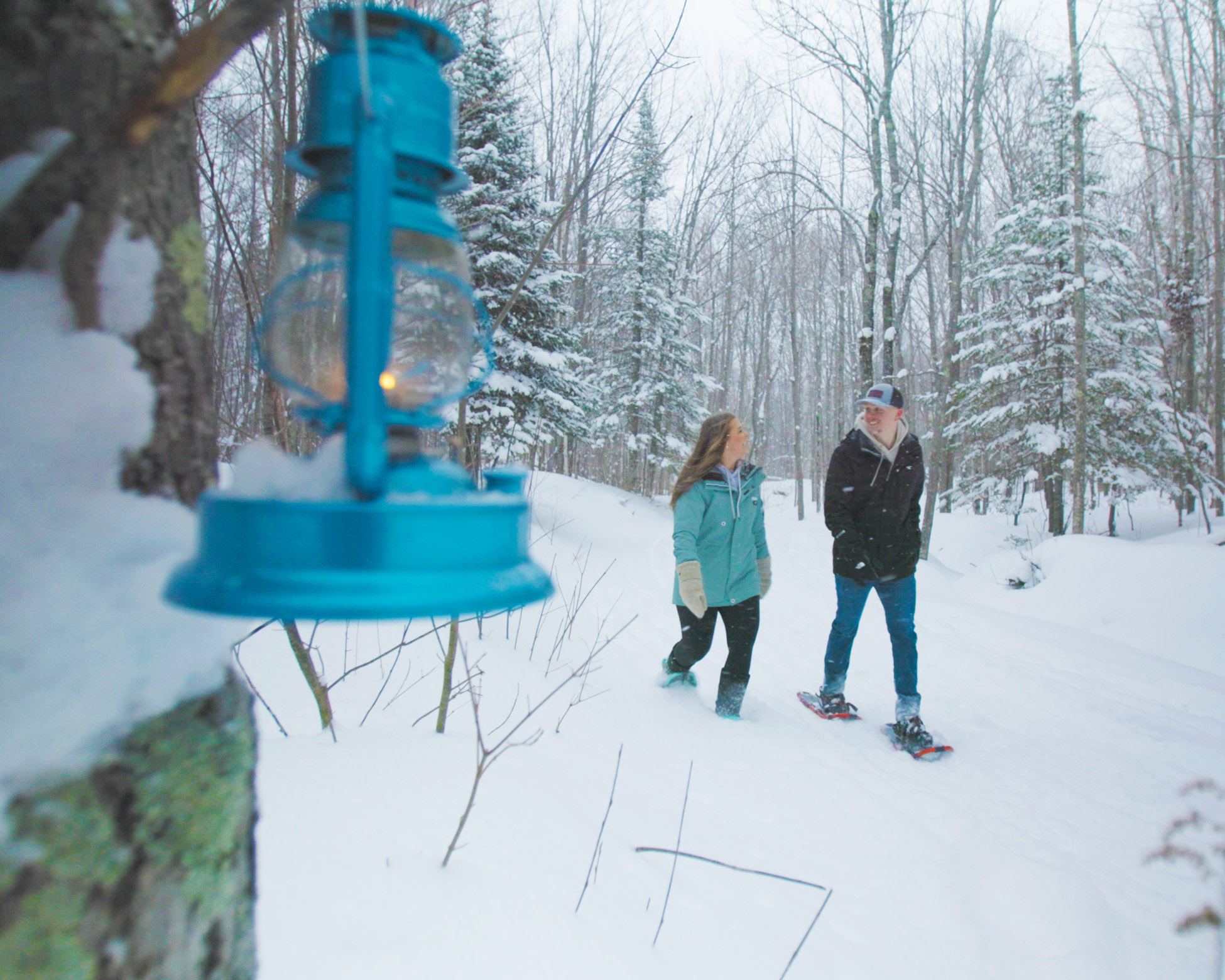 couple snowshoeing at lantern lit trail in porcupine mountains