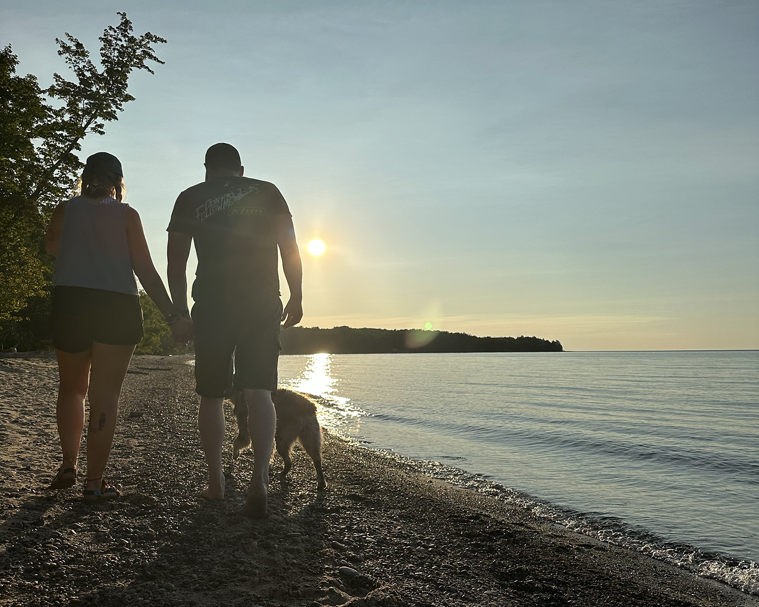 couple with dog on lake superior beach in porcupine mountains
